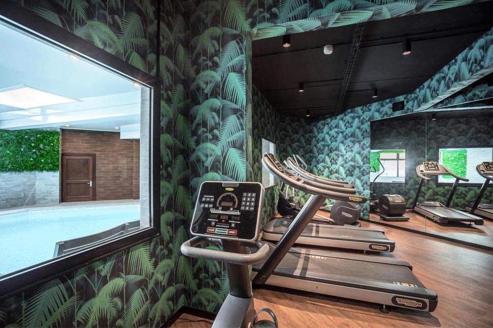 Salle de sport moderne avec tapis de course et murs végétalisés