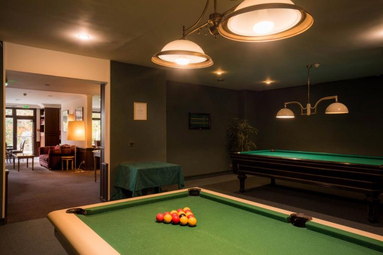 Salle de billard élégante avec deux tables et éclairage doux