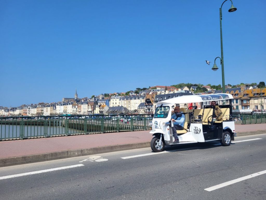 Tuk-tuk touristique devant ville côtière ensoleillée
